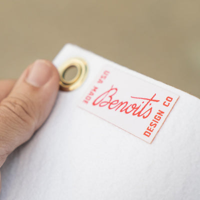 A hand holding a white tag with a red logo and text on it.