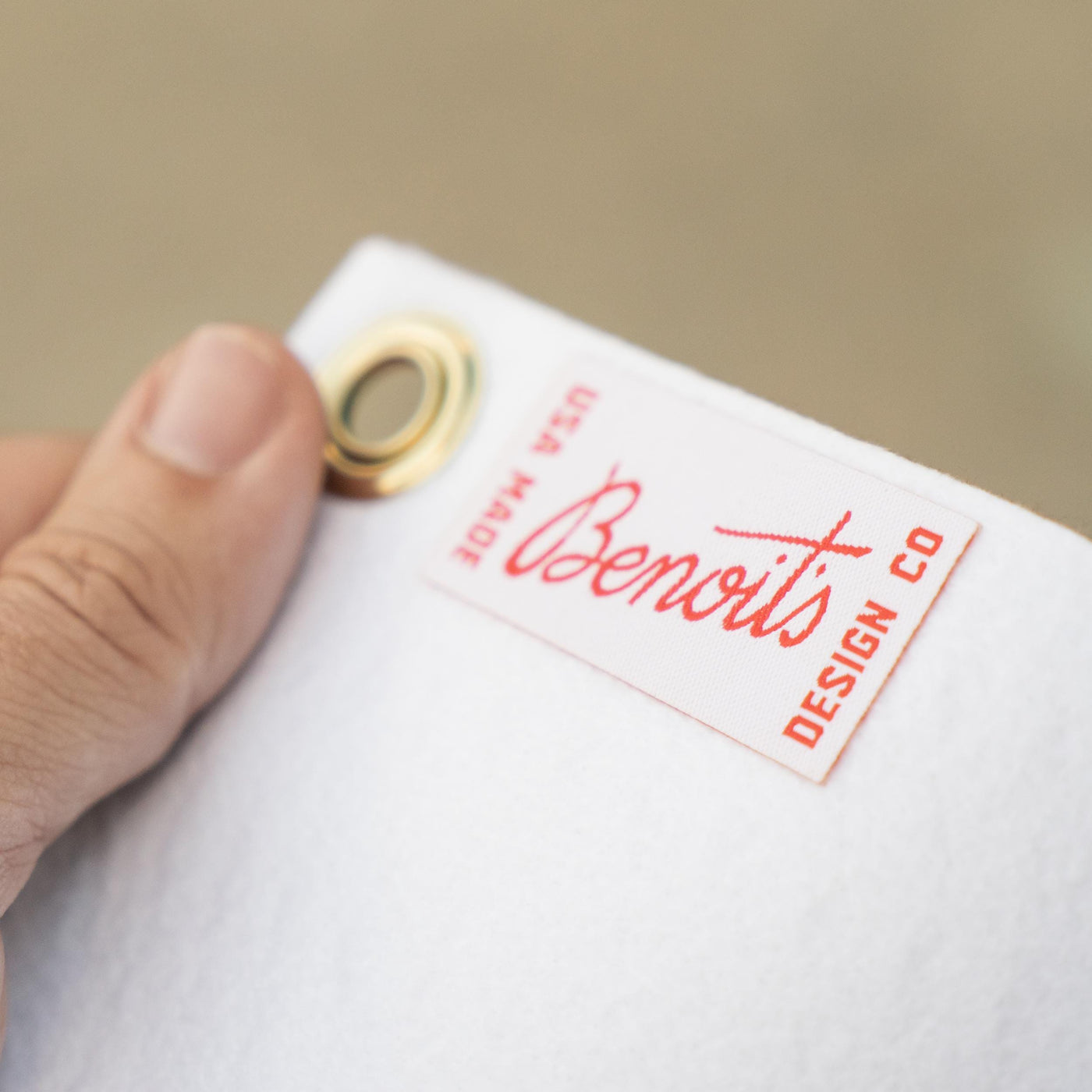 A hand holding a white tag with a red logo and text on it.