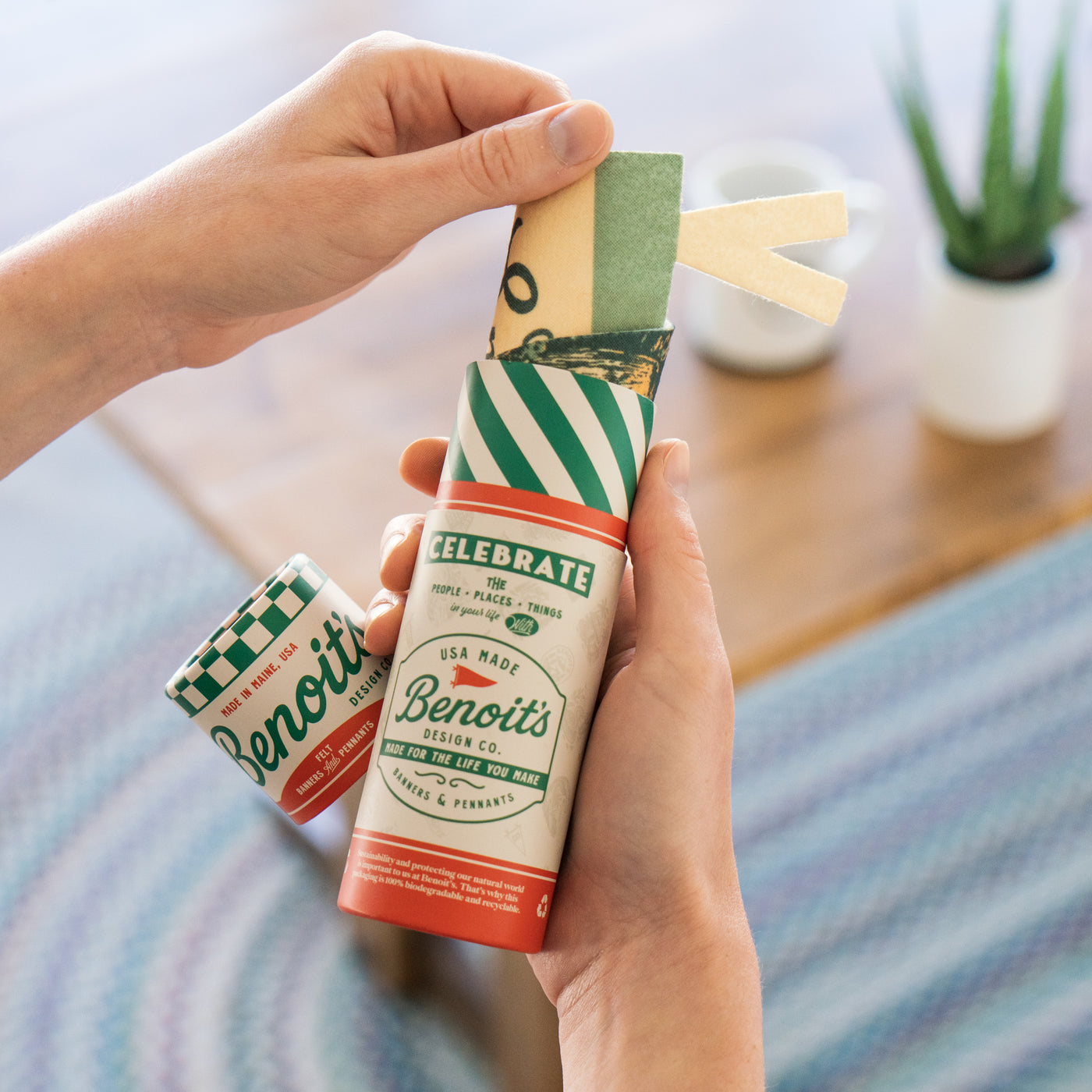 A person's hands holding a gift tube for Benoit's Design Co. product, which is a celebration of the people, places, and things in one's life.