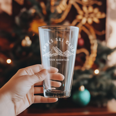 a person holding a glass in front of a christmas tree