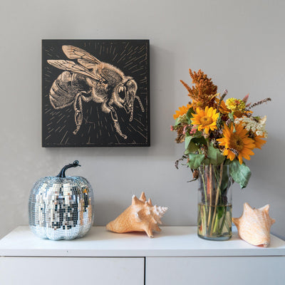 a vase filled with flowers next to a painting of a bee