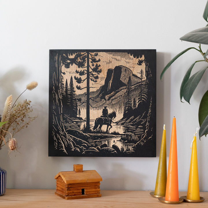 a picture of a man riding a horse in the woods