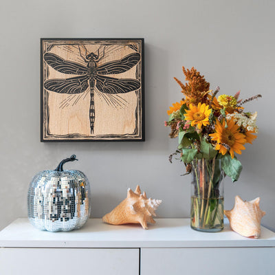 a vase filled with flowers next to a picture of a dragonfly