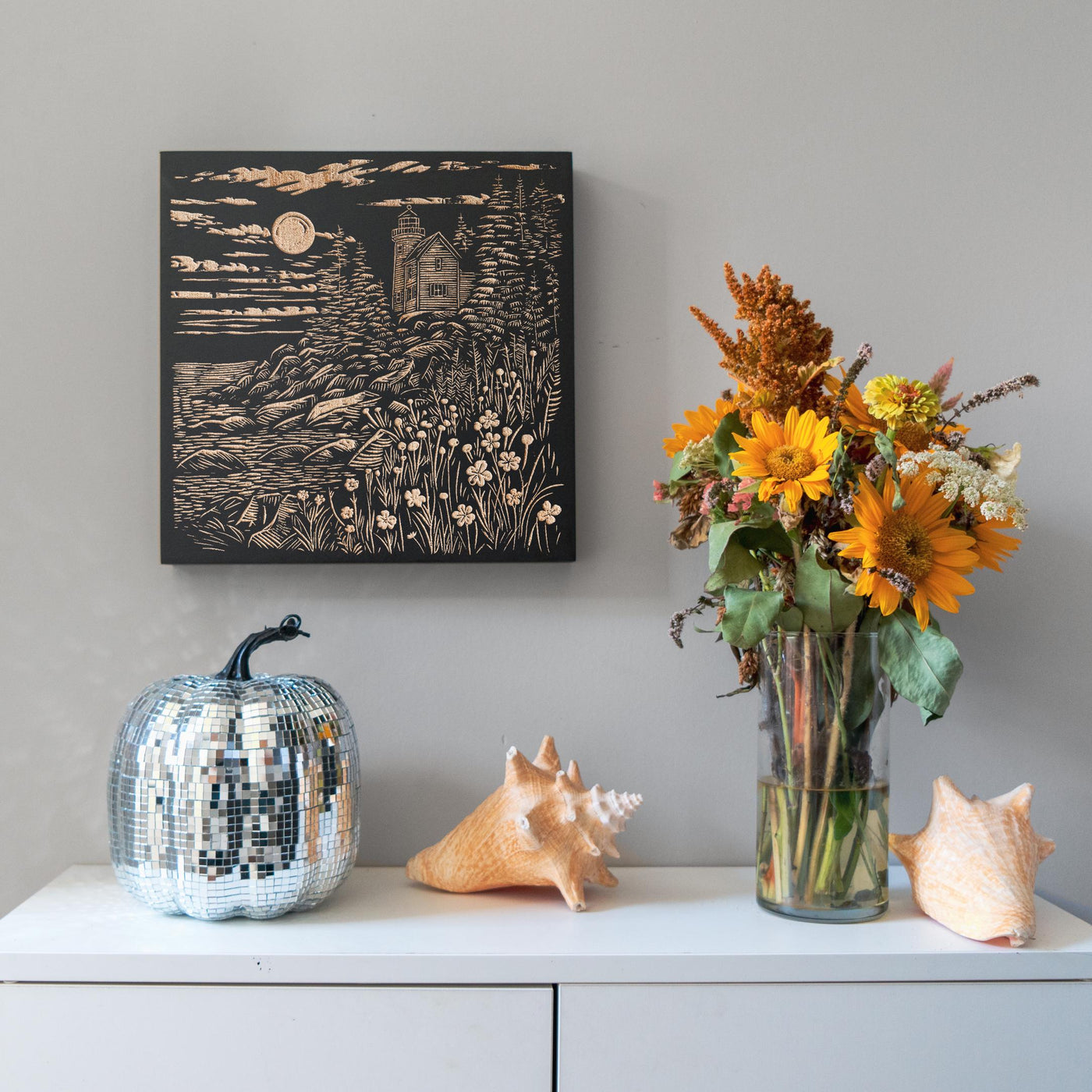 a vase filled with flowers next to a painting